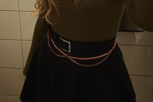 Person wearing a black skirt with a chain belt