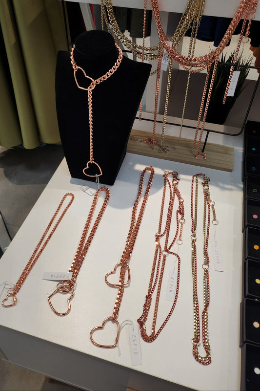 Rose gold necklaces displayed on a stand and table